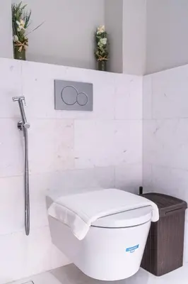 a white bathroom with a toilet and a basket at Palm Tower Palm Jumeirah Dubai in Dubai