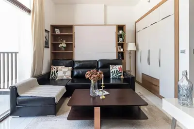 a living room with a black leather couch and a table at Frank Porter - Starz by Danube in Dubai