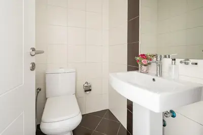 a white bathroom with a toilet and a sink at Frank Porter - Marina Wharf 2 in Dubai