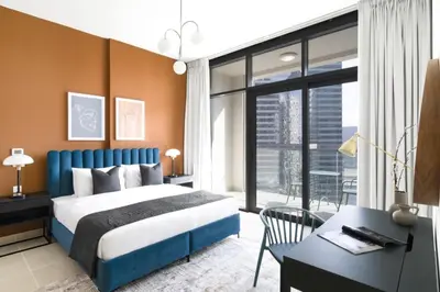 a bedroom with a blue bed and a desk and a window at Silkhaus unique 1BDR pad gorgeous view in new tower in Dubai
