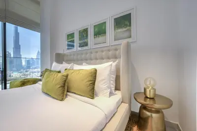 a bedroom with a white bed with green pillows at Maison Privee - Luxury Apt with Burj Khalifa Vw & Dubai Canal Access in Dubai