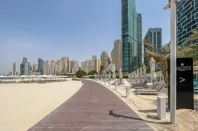a boardwalk leading to a beach with chairs and buildings at Frank Porter - The Address JBR in Dubai