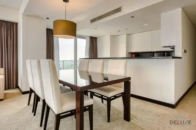 a dining room table with white chairs and a kitchen at Pristine 3BR at The Address Residences Dubai Marina by Deluxe Holiday Homes in Dubai