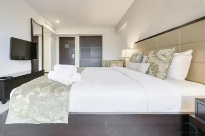 a bedroom with a large white bed and a flat screen tv at Regal Studio at The Address Residences Dubai Marina by Deluxe Holiday Homes in Dubai