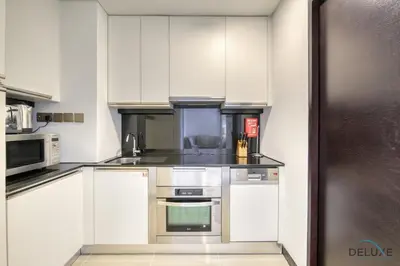 a kitchen with white cabinets and a stainless steel refrigerator at Upscale Studio at The Address Residences Dubai Marina by Deluxe Holiday Homes in Dubai