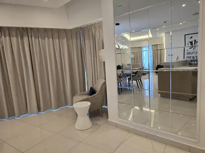 a living room with a chair and a glass wall at Quill Residence at Paramount Towers 3 BR Creek View in Dubai