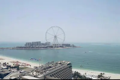 a beach with a ferris wheel in the water at Dubai marina sail in Dubai
