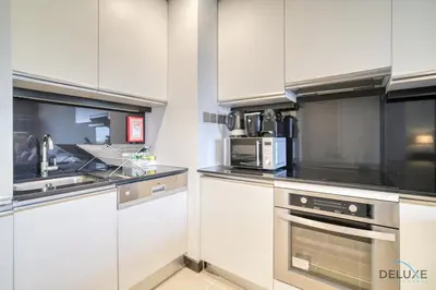 a kitchen with white cabinets and a stove top oven at Pristine 1BR in The Address Residences Dubai Marina by Deluxe Holiday Homes in Dubai