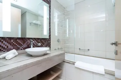 a bathroom with a sink and a tub and a mirror at GlobalStay DAMAC Towers by Paramount Business Bay Apartments in Dubai