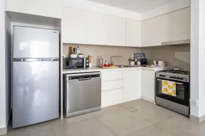 a kitchen with white cabinets and a stainless steel refrigerator at Frank Porter - Creek Horizon T2 in Dubai