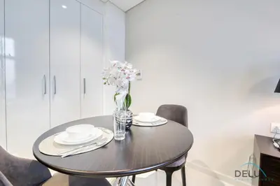 a dining room table with a vase of flowers on it at Sunlit Studio at Golf Promenade 2A DAMAC Hills By Deluxe Holiday Homes in Dubai
