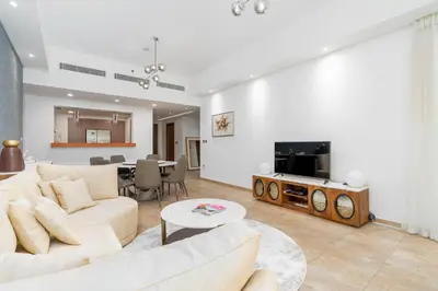 a living room with a couch and a tv at Ahlan HH - Luxurious Apartment with Beach Access and Sea View at Palm Jumeirah in Dubai