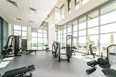 a gym with cardio equipment in a large room with windows at Livbnb - Tranquil 2BR in Bluewaters in Dubai