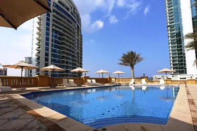 a swimming pool with chairs and umbrellas and a building at HiGuests - Charming Apt in JBR with Balcony by the Beach in Dubai