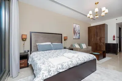 a bedroom with a large bed with blue pillows at White Sage - Elite Residence Studio in Dubai