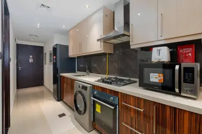 a kitchen with a stove and a washer and dryer at White Sage - Elite Residence Studio in Dubai