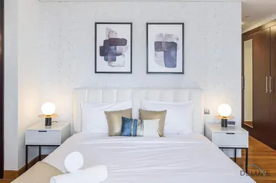 a bedroom with a large white bed with three pictures on the wall at Refreshing 1BR Loft At Sky Garden DIFC By Deluxe Holiday Homes in Dubai