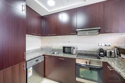 a kitchen with wooden cabinets and a microwave at Refreshing 1BR Loft At Sky Garden DIFC By Deluxe Holiday Homes in Dubai