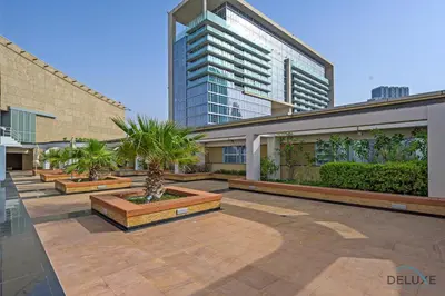 a courtyard with palm trees and a tall building at Refreshing 1BR Loft At Sky Garden DIFC By Deluxe Holiday Homes in Dubai
