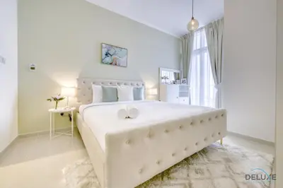 a white bedroom with a large bed and a window at Prime 1BR at Carson B DAMAC Hills Dubailand by Deluxe Holiday Homes in Dubai