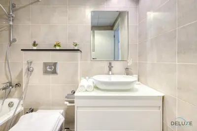 a bathroom with a sink and a mirror and a tub at Prime 1BR at Carson B DAMAC Hills Dubailand by Deluxe Holiday Homes in Dubai