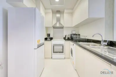a white kitchen with a sink and a dishwasher at Prime 1BR at Carson B DAMAC Hills Dubailand by Deluxe Holiday Homes in Dubai