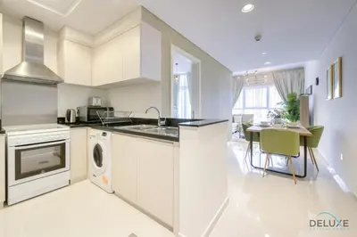 a white kitchen with a sink and a dishwasher at Prime 1BR at Carson B DAMAC Hills Dubailand by Deluxe Holiday Homes in Dubai