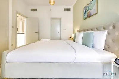 a white bedroom with a large white bed at Prime 1BR at Carson B DAMAC Hills Dubailand by Deluxe Holiday Homes in Dubai