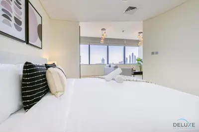 a bedroom with a large white bed and a living room at Calm Studio at Sky Gardens DIFC by Deluxe Holiday Homes in Dubai