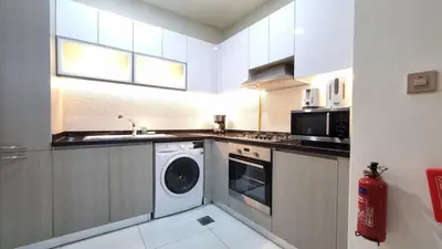 a kitchen with a washing machine and a sink at Spacious, Economical Apt Near Miralcz Garden in Dubai