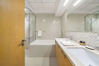a bathroom with a tub and a sink and a shower at Silkhaus Burj Khalifa view large 2BDR in great location in Dubai
