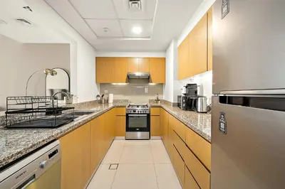 a large kitchen with wooden cabinets and stainless steel appliances at Silkhaus Burj Khalifa view large 2BDR in great location in Dubai