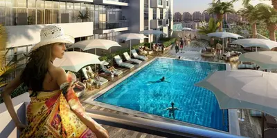 a woman in a hat standing next to a swimming pool at Luxury Escapes - Cozy Studio In front of Metro Stn - Access to Gym & Pool - Aura Azizi in Dubai