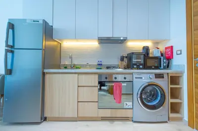 a kitchen with a refrigerator and a washing machine at Luxury Escapes - Cozy Studio In front of Metro Stn - Access to Gym & Pool - Aura Azizi in Dubai