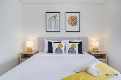 a bedroom with a large white bed with two lamps at Sunny Studio at Sky Gardens DIFC by Deluxe Holiday Homes in Dubai