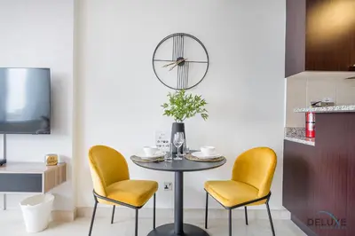 a dining room with a table and two chairs and a clock at Sunny Studio at Sky Gardens DIFC by Deluxe Holiday Homes in Dubai