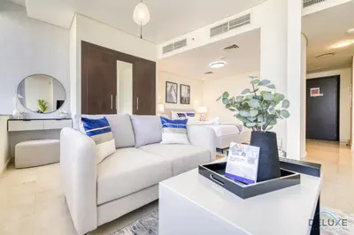 a living room with a white couch and a table at Best Value Modern 1BR with Pool & Stunning Views by Deluxe Holiday Homes in Dubai