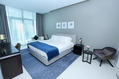 a hotel room with a bed and a chair at DAMAC MAISON PRIVE in Dubai