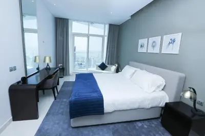 a hotel room with a bed and a desk and window at DAMAC MAISON PRIVE in Dubai