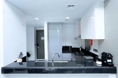 a kitchen with white cabinets and a black counter top at DAMAC MAISON PRIVE in Dubai