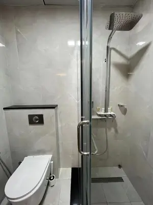 a bathroom with a toilet and a glass shower at Penrose Place Dubai JVC in Dubai