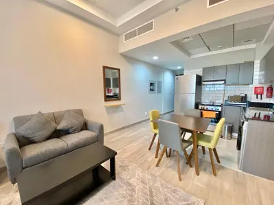 a living room and kitchen with a couch and a table at Penrose Place Dubai JVC in Dubai