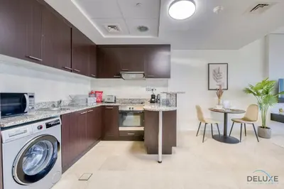 a kitchen with a washing machine and a table at Opulent Studio at Sky Gardens DIFC by Deluxe Holiday Homes in Dubai