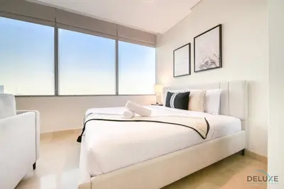 a white bedroom with a large white bed with windows at Opulent Studio at Sky Gardens DIFC by Deluxe Holiday Homes in Dubai