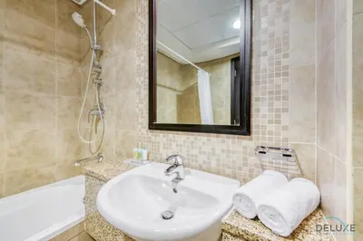 a bathroom with a sink and a mirror and a tub at Opulent Studio at Sky Gardens DIFC by Deluxe Holiday Homes in Dubai