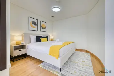 a bedroom with a large bed with a yellow blanket at Affordable Luxury Modern 1BR with Pool & Balcony by Deluxe Holiday Homes in Dubai