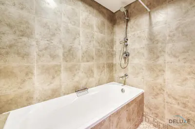 a bathroom with a tub and a shower at Affordable Luxury Modern 1BR with Pool & Balcony by Deluxe Holiday Homes in Dubai