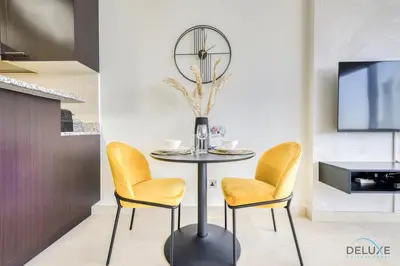 a dining room with a table with chairs and a clock at Affordable Luxury Modern 1BR with Pool & Balcony by Deluxe Holiday Homes in Dubai
