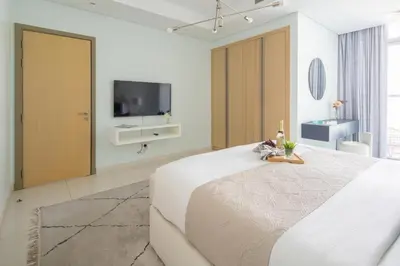 a white bedroom with a large bed and a tv at Frank Porter - Paramount Midtown in Dubai