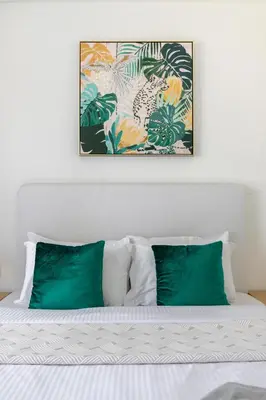 a bed with green pillows and a picture above it at Frank Porter - Paramount Midtown in Dubai